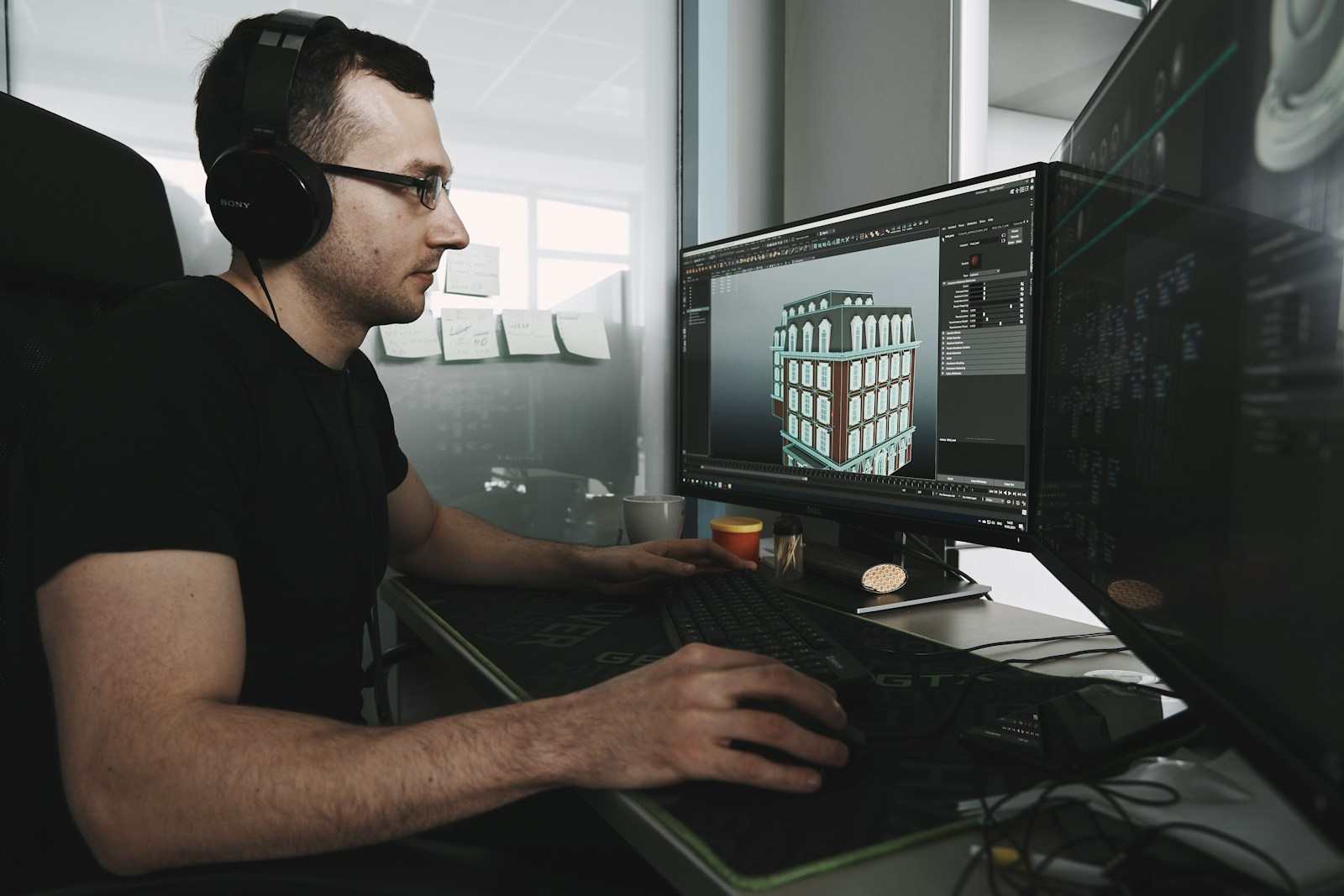 Side profile of a male 3D animator wearing Sony headphones and glasses, intensely focused on his dual screen display showing specialized software rendering a detailed classical four-story building facade in an office environment near Mission District, San Francisco CA. This image captures the essence of modern architectural visualization work, showing a focused professional wearing headphones and glasses while creating a detailed 3D model of a multi-story building. Utilizing a powerful dual-monitor setup in a bright office setting near Mission Dolores Park in San Francisco, the designer demonstrates the precision required for digital design and asset creation. This expertise is crucial for real estate development and visualization projects across the Bay Area.