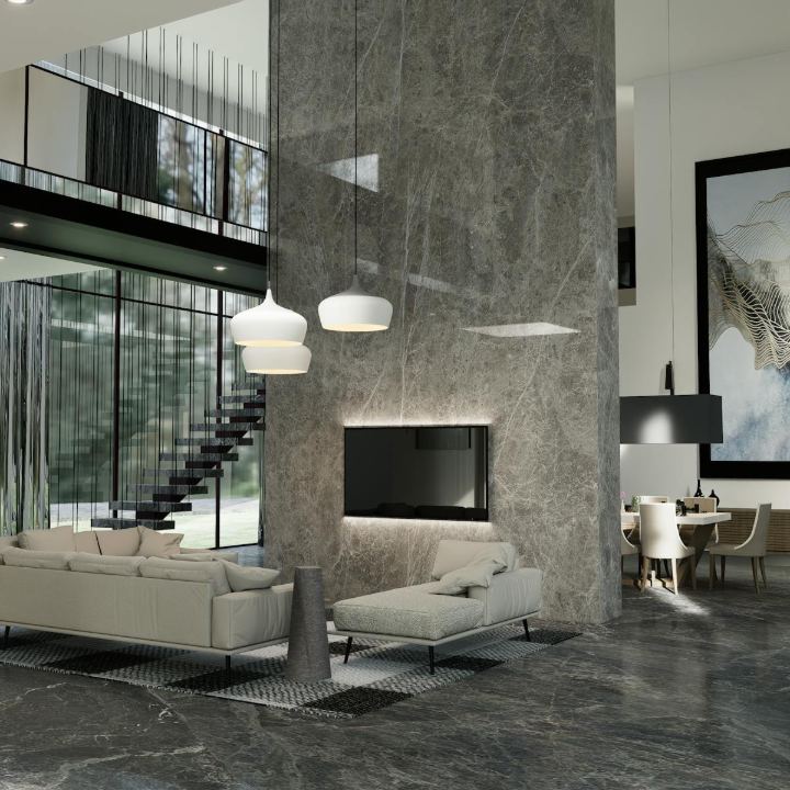 Dramatic modern living space featuring a floor-to-ceiling gray veined marble accent wall and floor, neutral contemporary seating, and a floating staircase behind full-height glass windows, representing luxury interior design standards near the Mission District, San Francisco. This exquisite residential interior showcases a dedication to modern luxury and high-quality materials. The central feature is a massive stone column that serves as a backdrop for the integrated television and separates the living room from the dining area. Expansive glass walls and a sleek, open riser staircase contribute to the airy, multi-story design, creating an ideal setting for sophisticated entertaining and contemporary living in San Francisco.