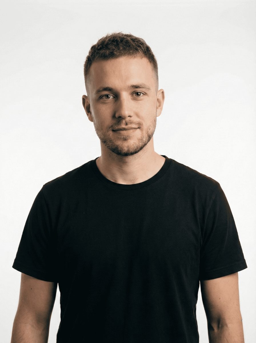 Professional headshot of a smiling young white man with short brown hair and light stubble, wearing a casual black t-shirt, representing a business leader in San Francisco, CA. This modern portrait captures an approachable young professional ready to assist clients throughout the San Francisco area, particularly near the Mission District locale. The image conveys reliability and a contemporary business aesthetic, ideal for an About Us page or staff directory focusing on local expertise and customer service in the Bay Area market.