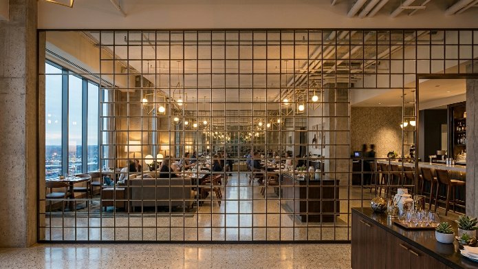 A decorative bronze square grid screen separates a dining room with patrons from the foreground.